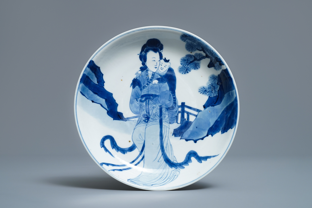 Een Chinees blauw-wit semi-eierschaal bord met een dame die een kind draagt, Kangxi