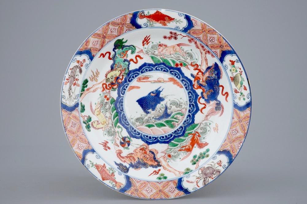 Un plat en porcelaine de Chine famille verte &agrave; d&eacute;cor d'une carpe entour&eacute;e de chevaux et lions bouddhistes, Kangxi