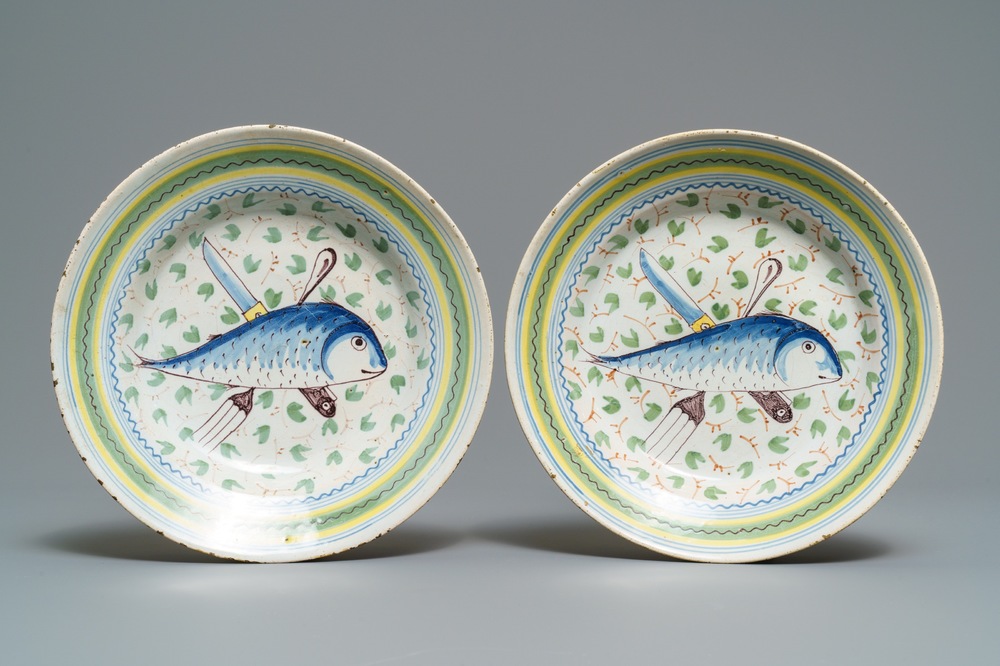 Une paire d' assiettes en fa&iuml;ence de Bruxelles polychrome &agrave; d&eacute;cor de poissons et couverts, 18&egrave;me