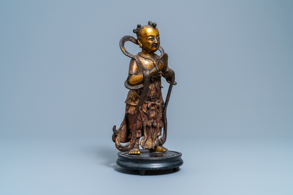 Een Chinese gelakte en vergulde bronzen figuur van een dienaar, Ming