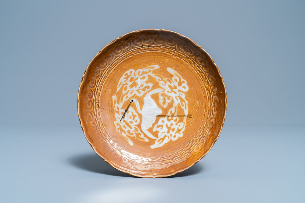 Een zeldzaam Chinees Swatow bord met een ooievaar op bruine fondkleur, Ming