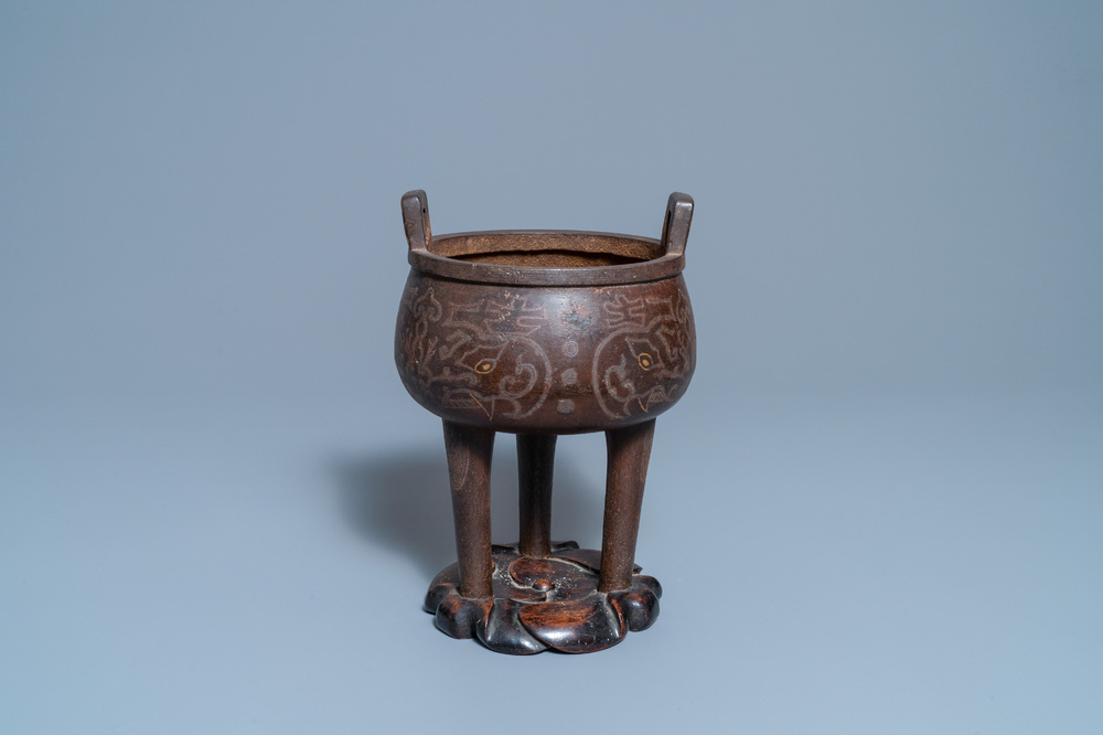 A Chinese inlaid bronze tripod censer on wooden stand, Ming