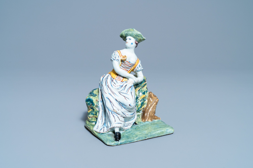 A polychrome Dutch Delft figure of a seated lady, 18th C.