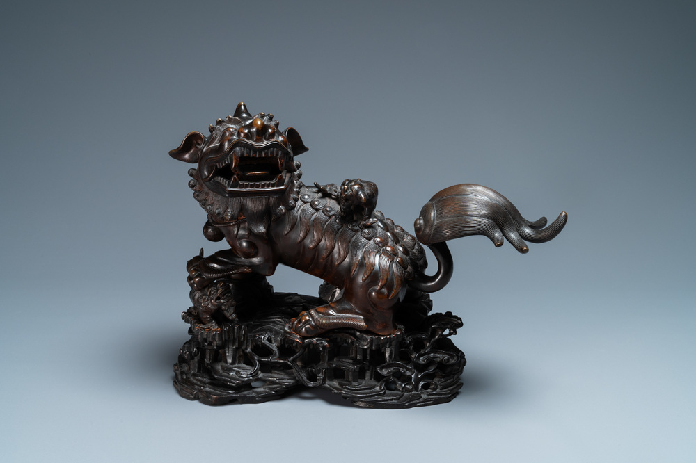 Un mod&egrave;le d'un lion bouddhiste en bronze sur socle en bois sculpt&eacute;, Chine, 18&egrave;me