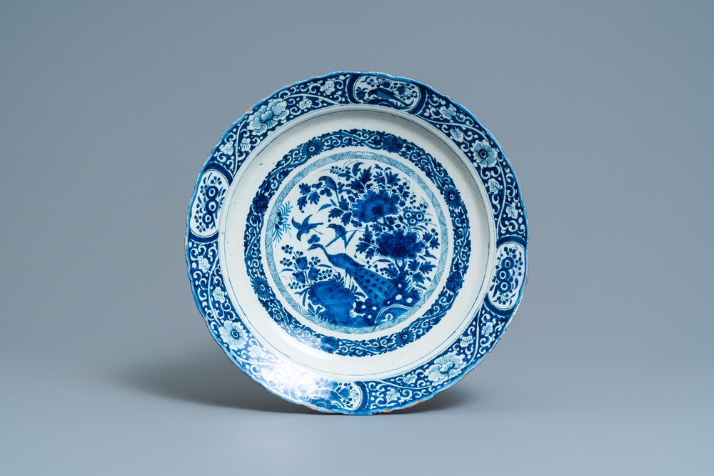 A Dutch Delft blue and white dish with a peacock in a Chinese garden, dated 1693