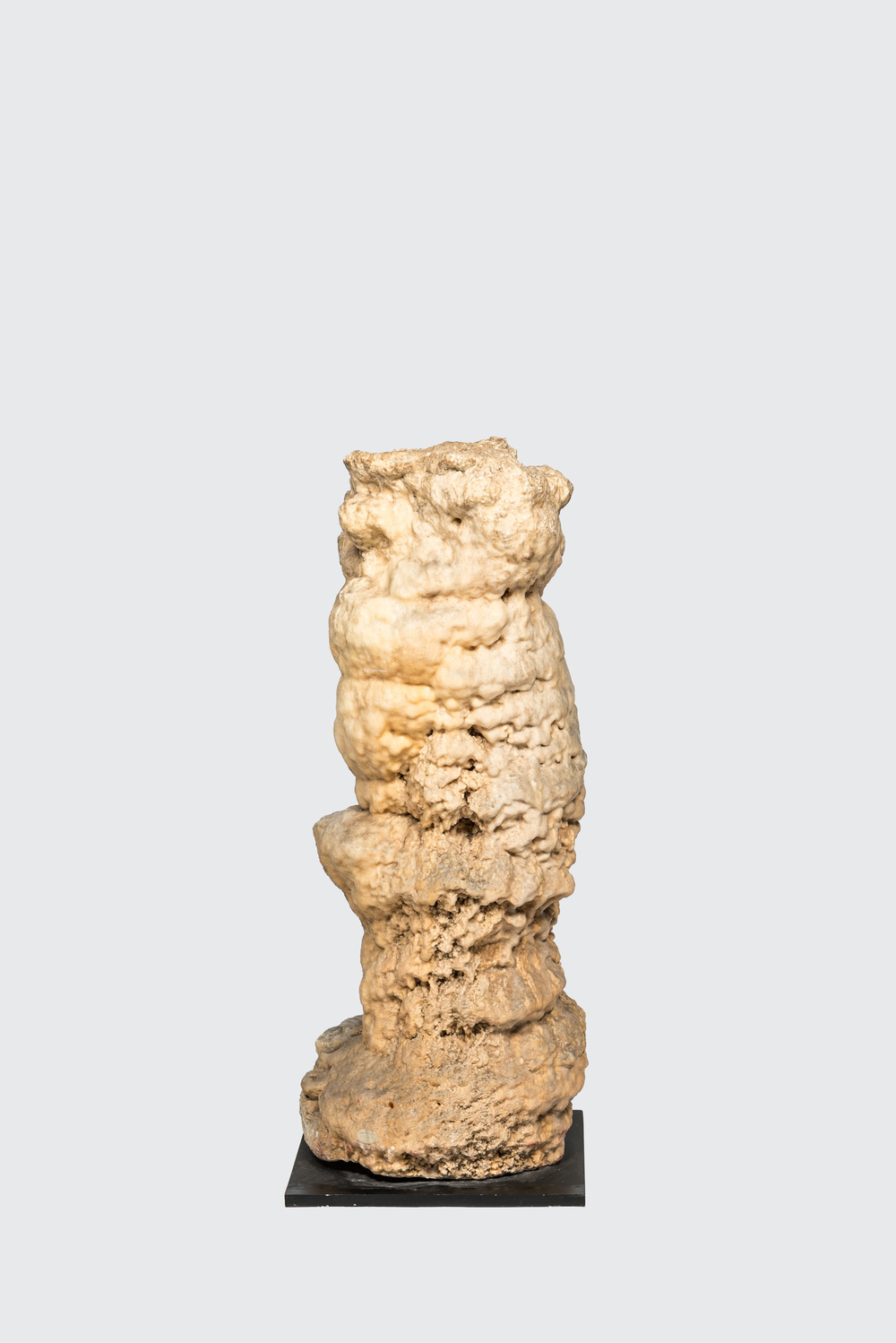 A large stalagmite specimen on a square wooden base