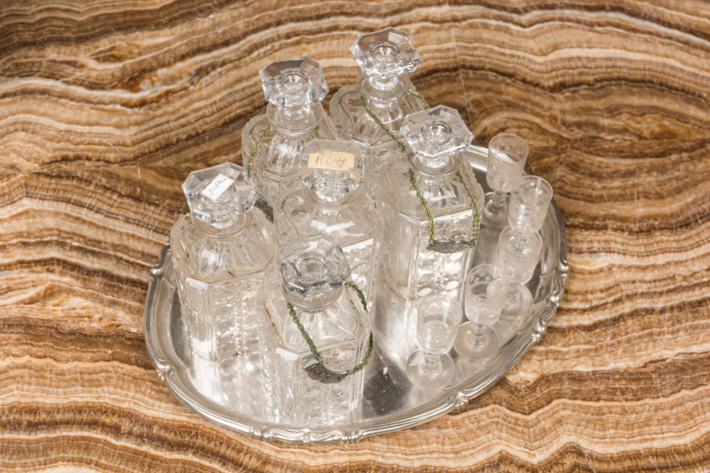 Zes gefacetteerde glazen likeurflessen en vijf geslepen glaasjes op een verzilverd dienblad, 20e eeuw