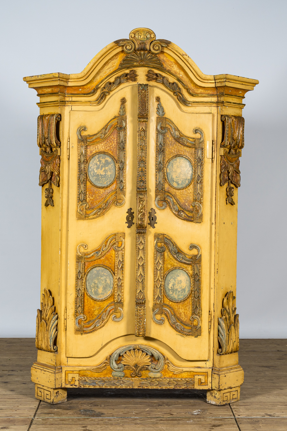 A German patinated wooden two-door cabinet with relief design and monogram R.K., 19th C.