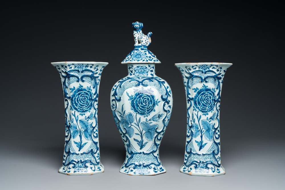 A Dutch Delft blue and white garniture of three vases with a large rose, 18th C.