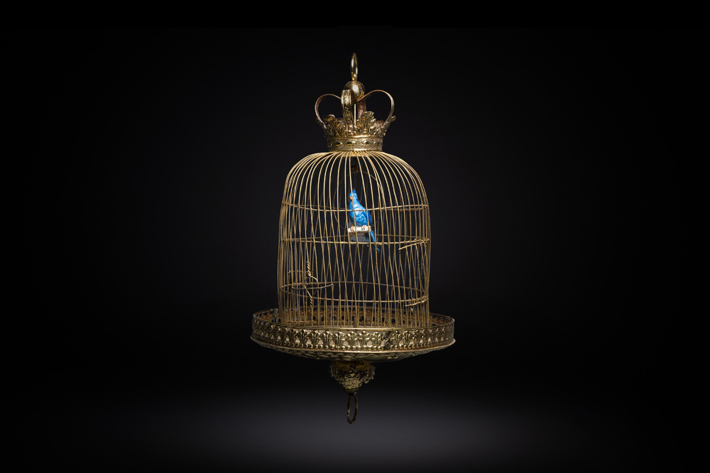 A Dutch or Flemish yellow brass bird cage with a porcelain bird, 18th and 19th C.