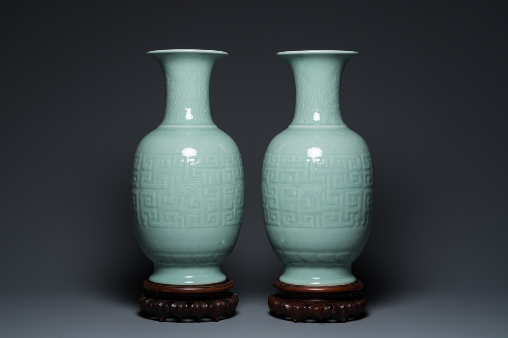 Een paar Chinese monochrome celadon vazen met onderglazuur decor op houten sokkels, Qianlong merk, 18/19e eeuw