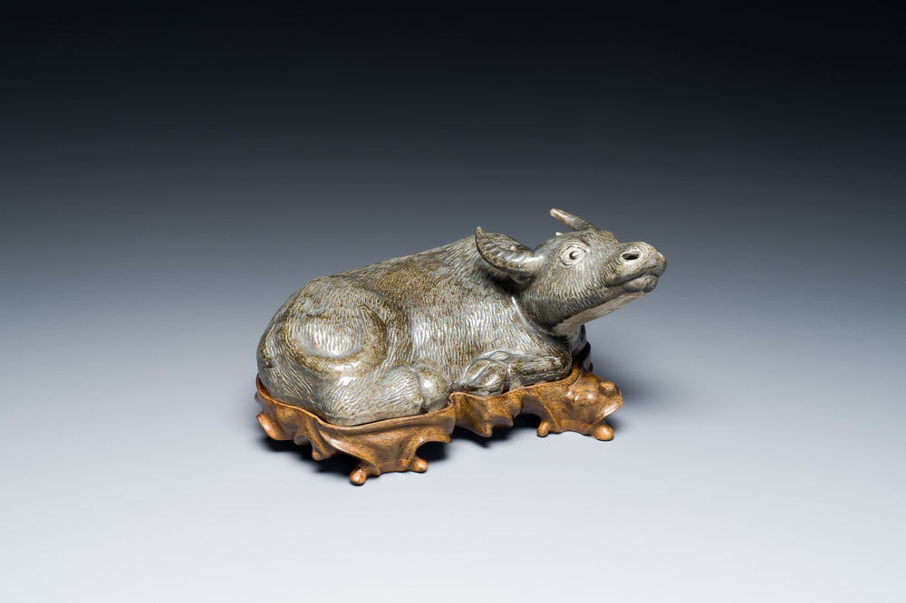 A Chinese monochrome brown-grey-glazed sculpture of a reclining water buffalo on wooden stand, 19th C.