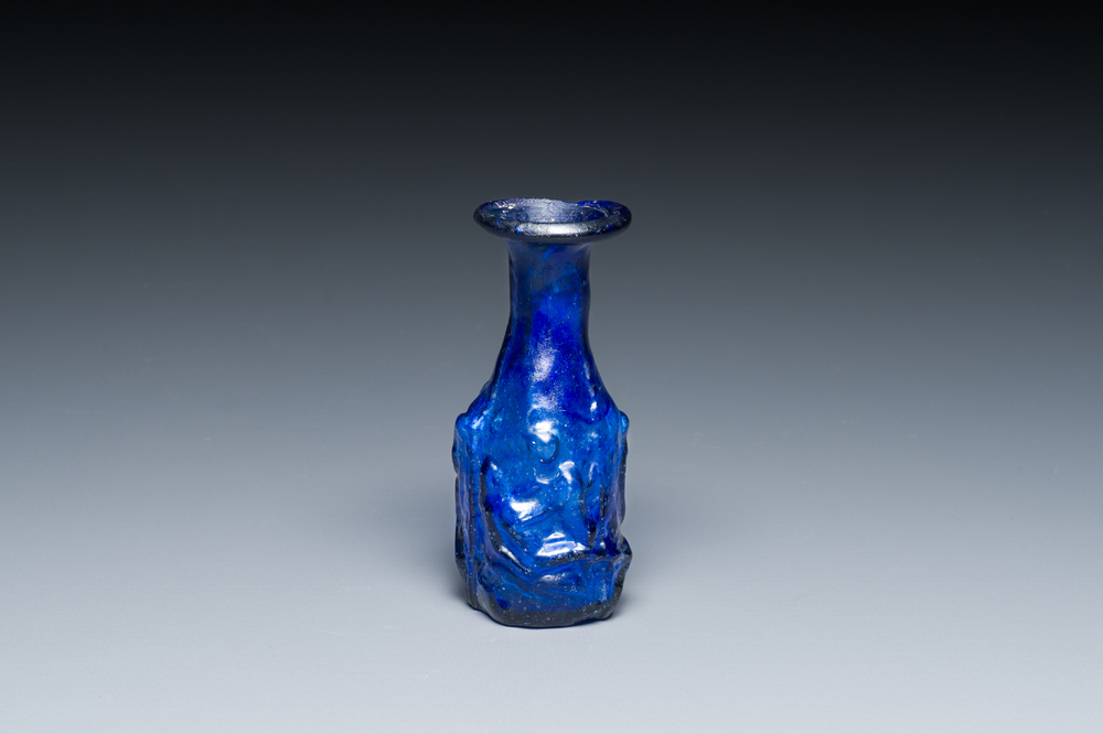 A Roman &lsquo;Sidonian&rsquo; dark blue 'erotic subject' molded glass bottle, Eastern Mediterranean, ca. 1st C.