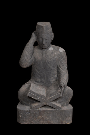 Een basalten sculptuur van een lezende student, Indonesië, 20e eeuw