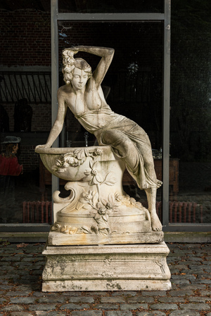 A white painted concrete garden urn flanked by the goddess Flora on matching stand, 20th C.